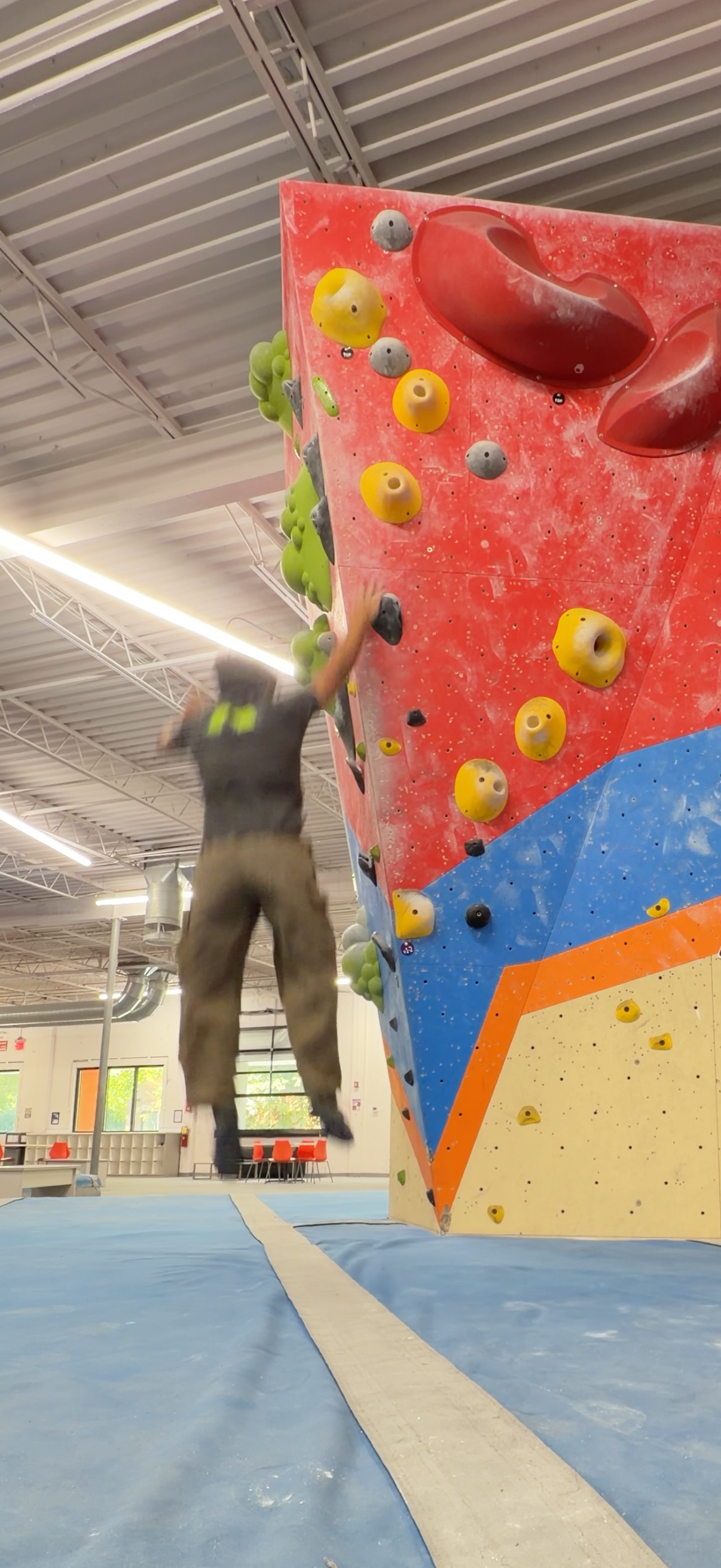 Falling onto the mats after reaching the top of an indoor climbing wall