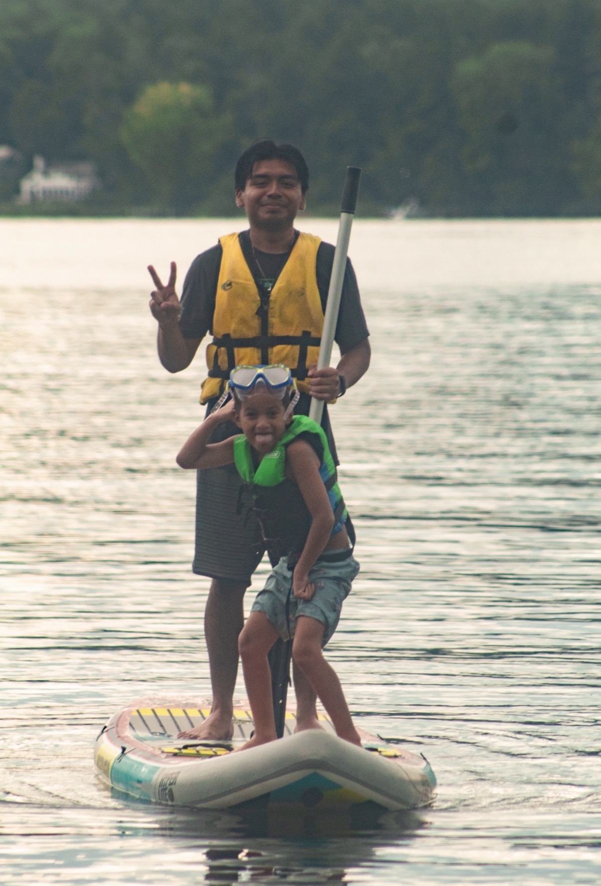 Two people wearing life jackets on a paddleboard